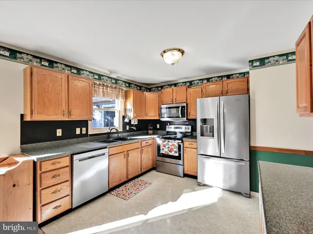 a kitchen with stainless steel appliances granite countertop a refrigerator a stove a sink and a microwave