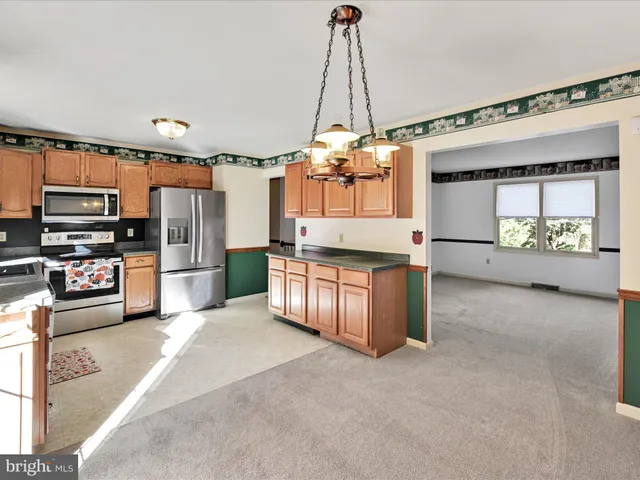 a large kitchen with stainless steel appliances kitchen island granite countertop a refrigerator oven a sink and dishwasher