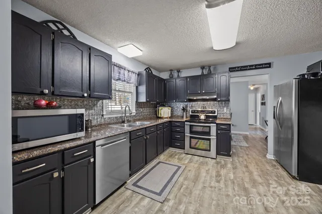 a kitchen with stainless steel appliances granite countertop a refrigerator a stove top oven a sink and dishwasher