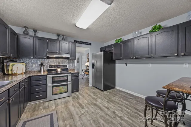 a kitchen with kitchen island granite countertop wooden cabinets and stainless steel appliances