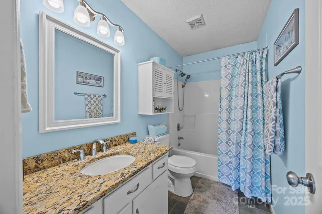a bathroom with a granite countertop sink toilet and shower
