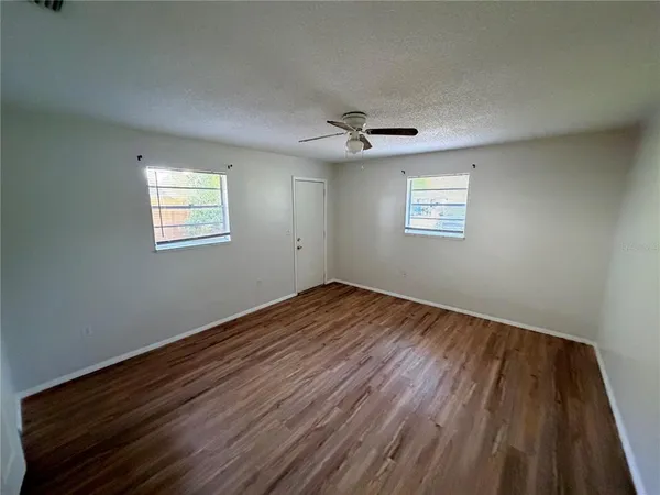 a view of empty room with wooden floor and fan