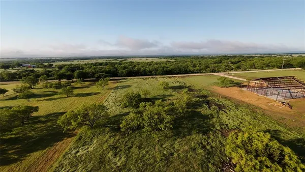 an aerial view of a residential houses with outdoor space and trees