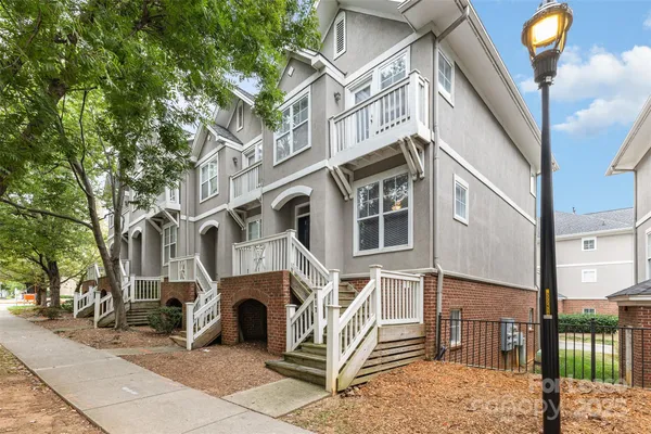 a view of a white house with iron fence and large windows
