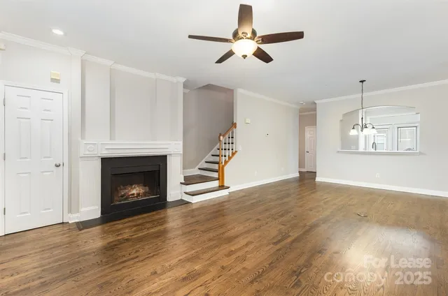 a view of an empty room with wooden floor fireplace and a window