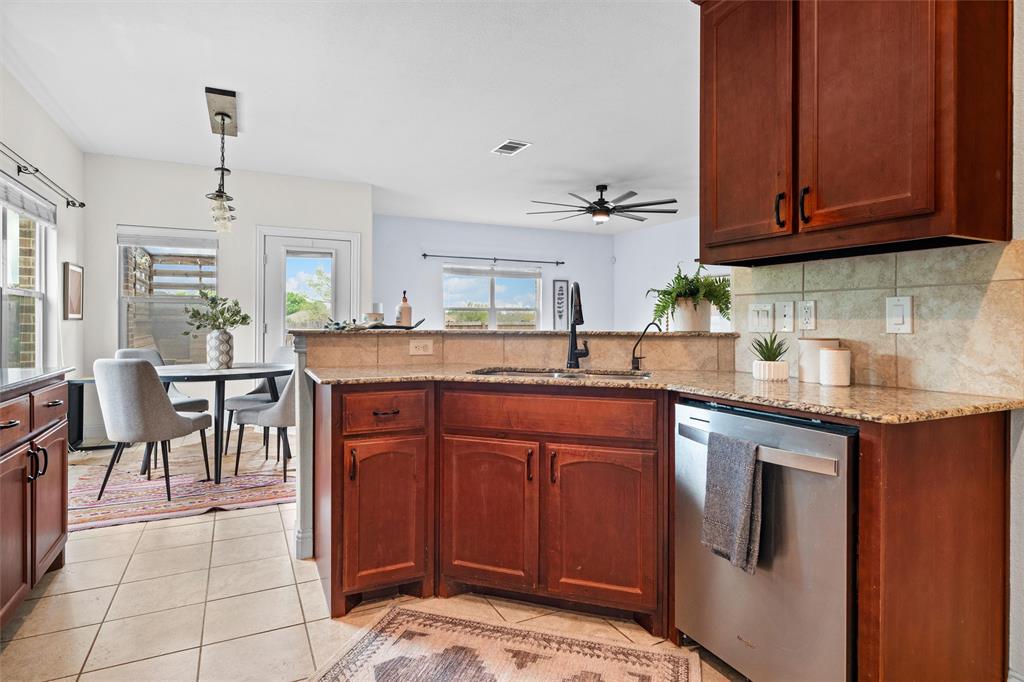 2322 Trace Ridge Drive Weatherford, TX 76087 - Photo 11 of 30 Kitchen with light stone countertops, a peninsula, stainless steel dishwasher, hanging light fixtures, and light tile patterned floors