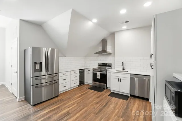 a kitchen with cabinets stainless steel appliances and wooden floor