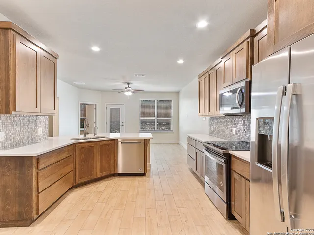 a large kitchen with stainless steel appliances granite countertop a refrigerator and a stove top oven