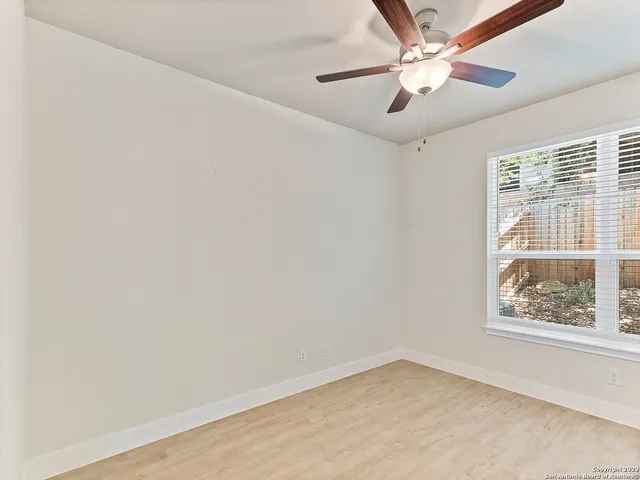 an empty room with a window and a fan