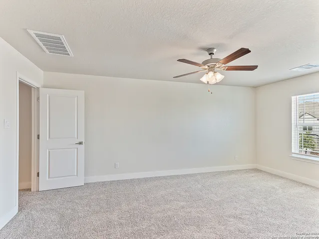 an empty room with windows and fan