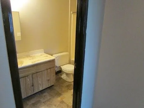 a bathroom with a granite countertop toilet and a sink