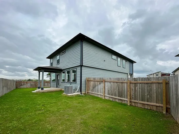 a backyard of a house with lots of green space and wooden fence