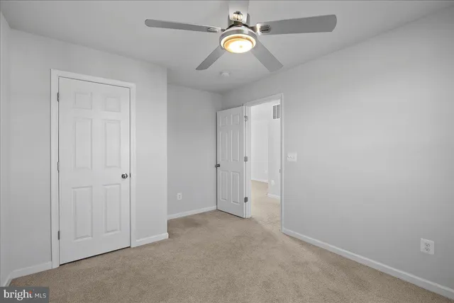 an empty room with closet and fan