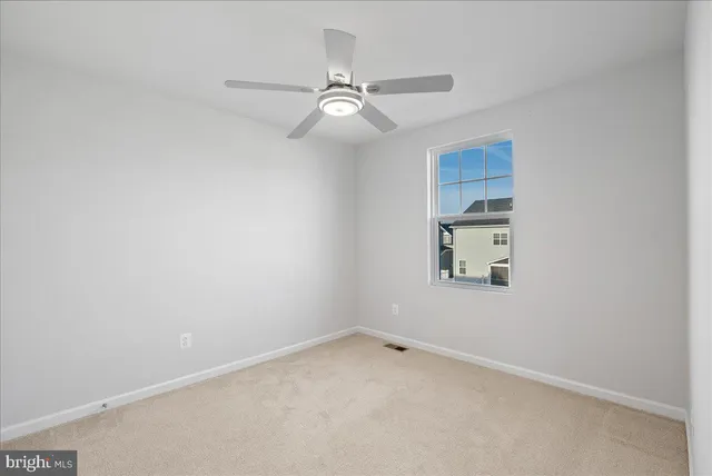 an empty room with a window and ceiling fan
