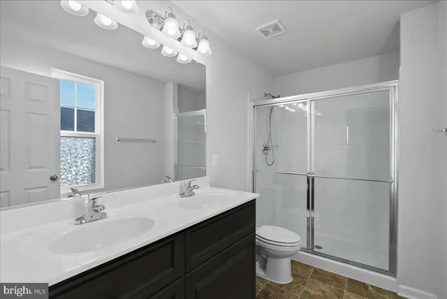 a bathroom with a double vanity sink toilet and a mirror