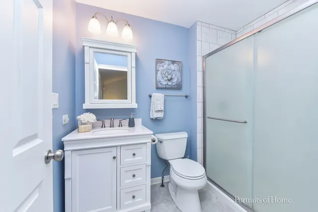 a bathroom with a toilet sink vanity and mirror