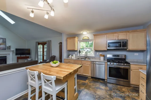 a kitchen with kitchen island granite countertop a stove a sink a dining table and chairs