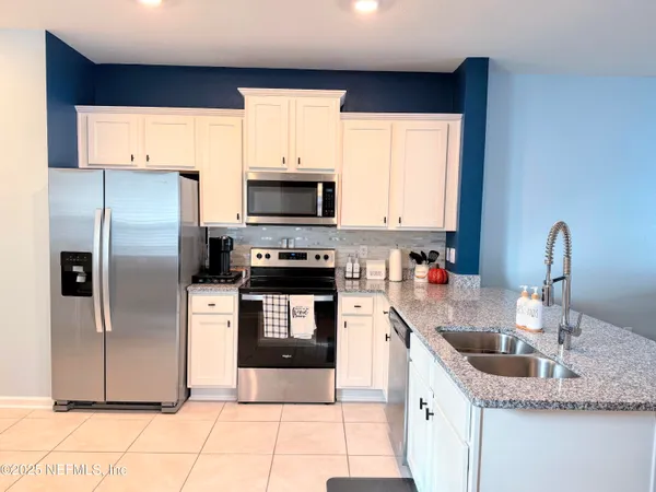 a kitchen with stainless steel appliances granite countertop a sink a refrigerator and a granite counter tops