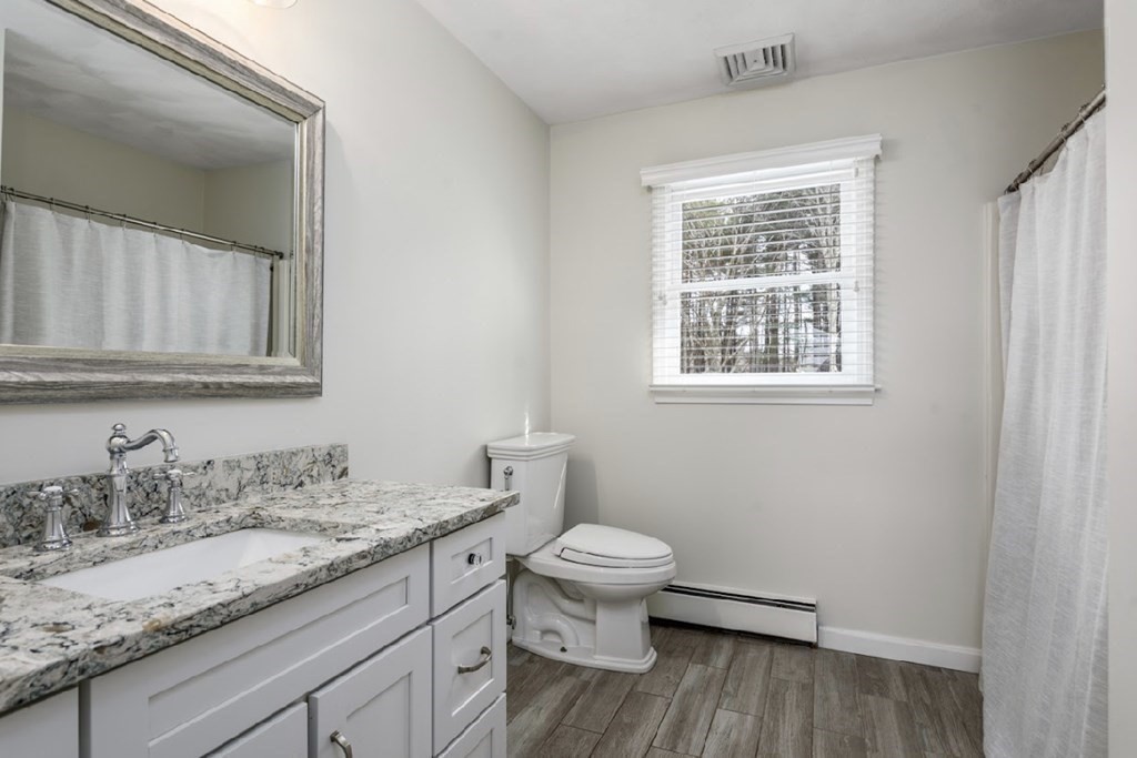 11 Woodman Road Amesbury, MA 01913 - Photo 22 of 31 a bathroom with a granite countertop toilet a sink and a window