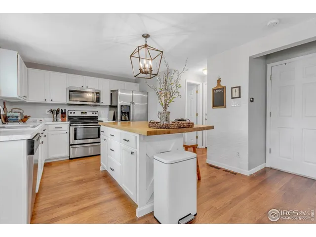 a kitchen with stainless steel appliances granite countertop a refrigerator a stove oven a sink dishwasher and white cabinets with wooden floor