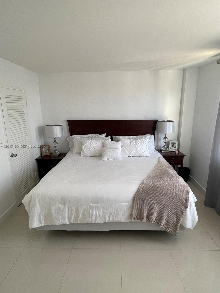 9195 Collins Avenue, Unit 1012 Surfside, FL 33154 - Photo 12 of 27 a bedroom with a bed and a night stand