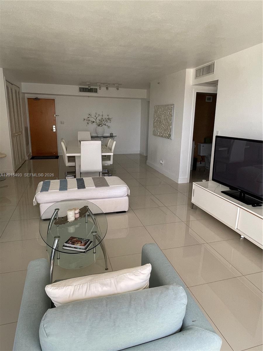 9195 Collins Avenue, Unit 1012 Surfside, FL 33154 - Photo 2 of 27 a living room with a couch and a table