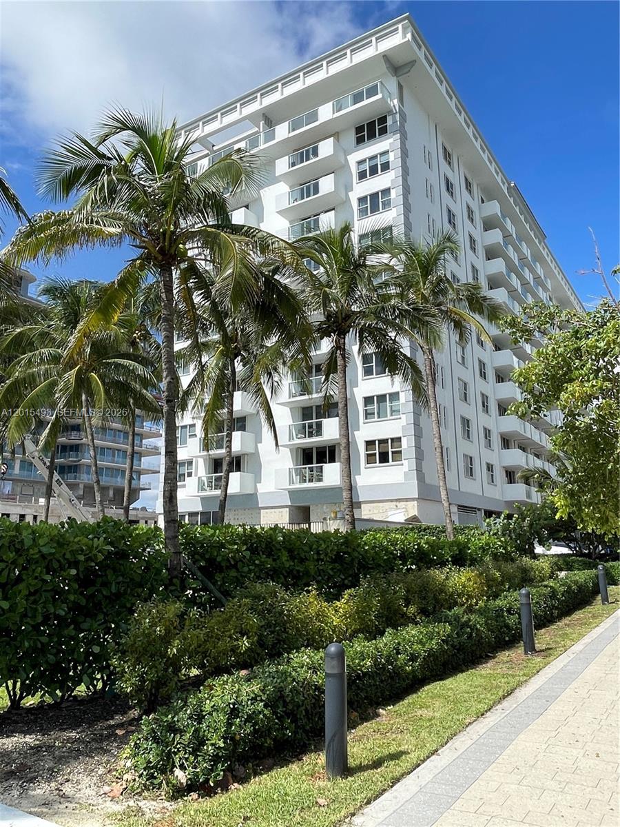 9195 Collins Avenue, Unit 1012 Surfside, FL 33154 - Photo 25 of 27 a front view of a multi story residential apartment building with yard and sign board