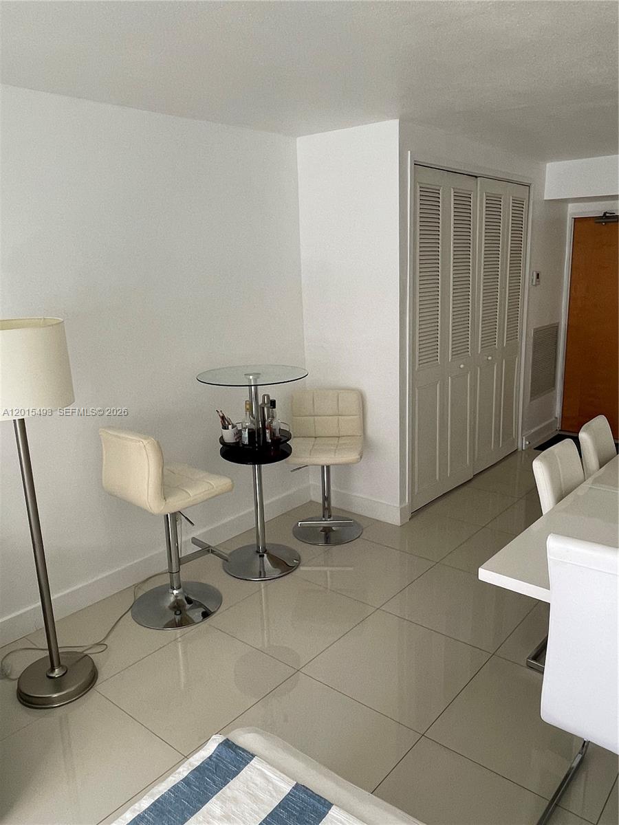 9195 Collins Avenue, Unit 1012 Surfside, FL 33154 - Photo 5 of 27 a living room with furniture a mirror and a lamp