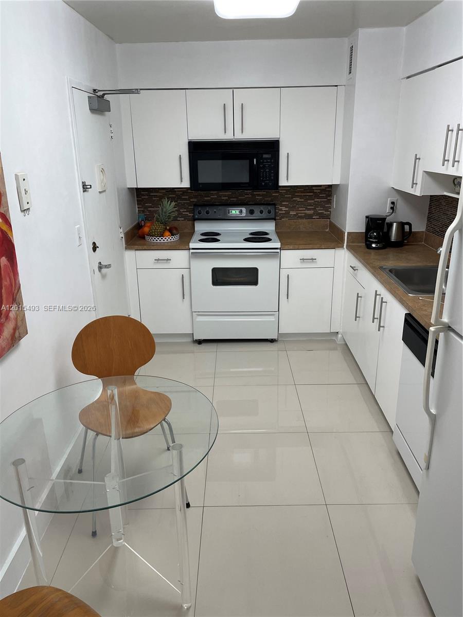 9195 Collins Avenue, Unit 1012 Surfside, FL 33154 - Photo 8 of 27 a kitchen with stainless steel appliances a stove a sink and a cabinets