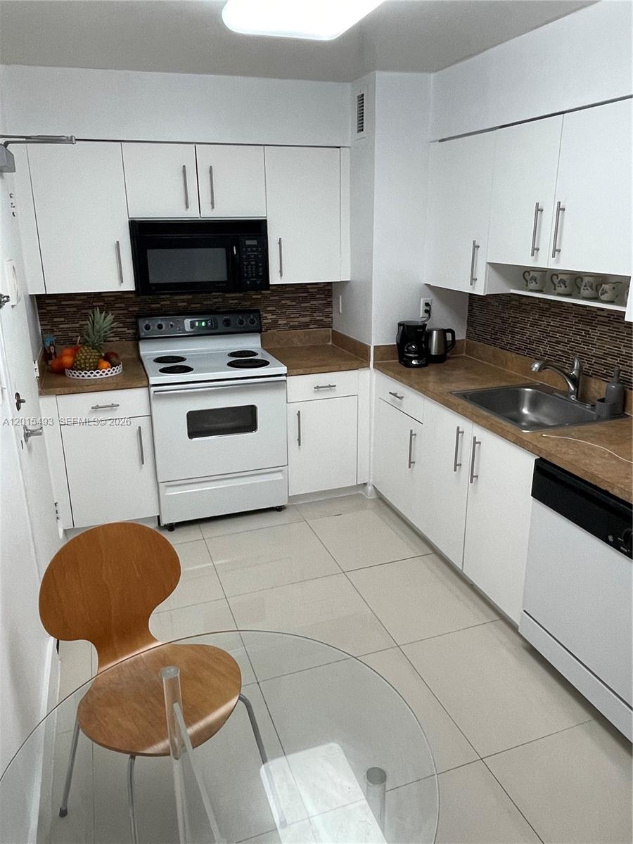 9195 Collins Avenue, Unit 1012 Surfside, FL 33154 - Photo 9 of 27 a kitchen with stainless steel appliances a stove a sink and a white cabinets