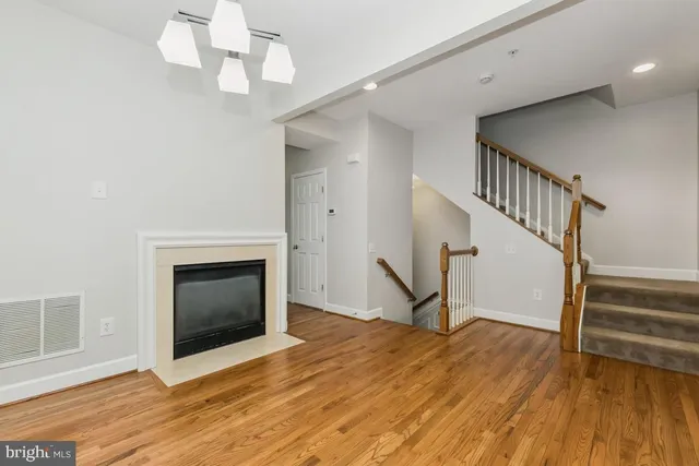 a view of a livingroom with wooden floor staircase and a kitchen