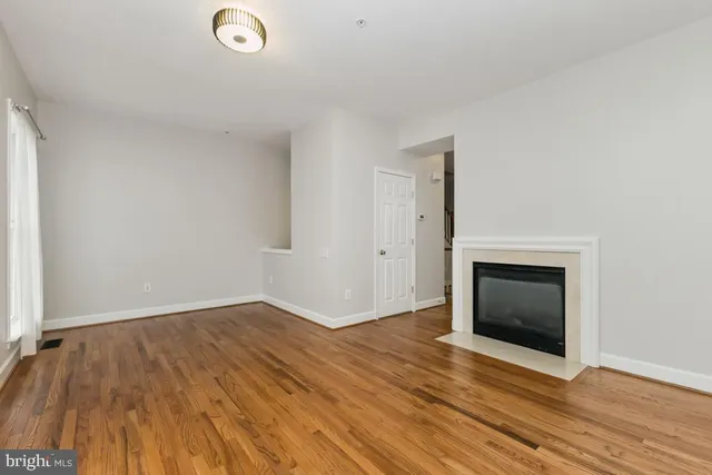 an empty room with wooden floor and fireplace
