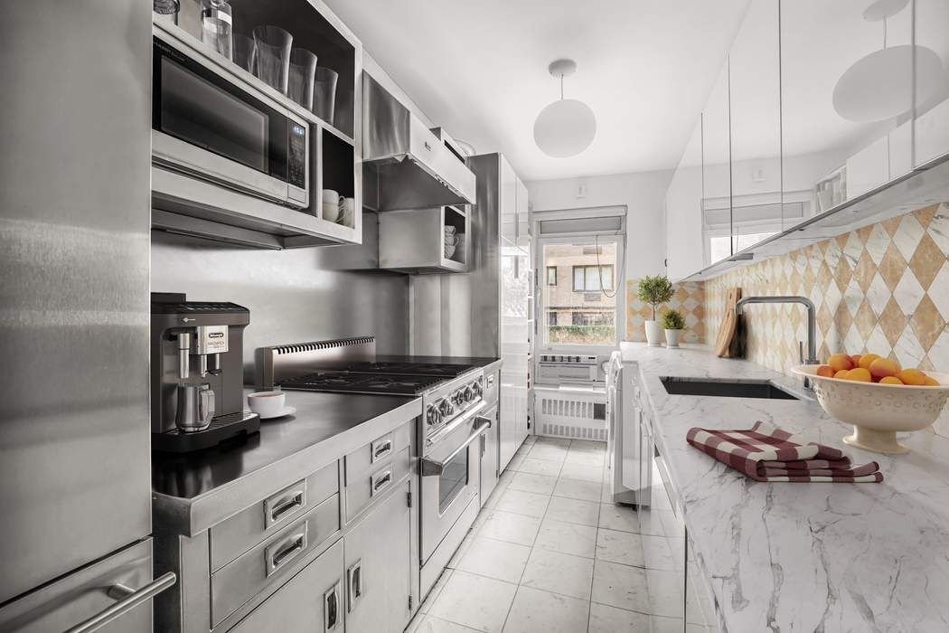 1050 5th Avenue, Unit 3B Manhattan, NY 10028 - Photo 7 of 13 a kitchen with stainless steel appliances granite countertop a stove and cabinets
