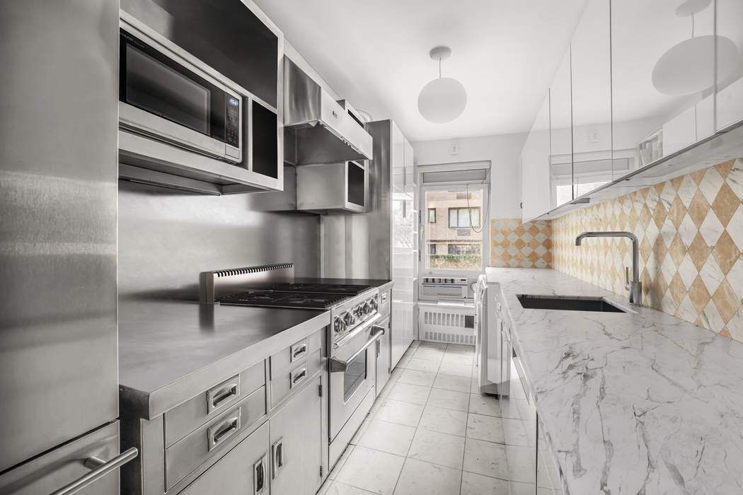 1050 5th Avenue, Unit 3B Manhattan, NY 10028 - Photo 8 of 13 a kitchen with stainless steel appliances granite countertop a stove and cabinets