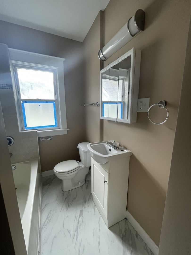 710 North Poplar Street, Unit 2 Waukegan, IL 60085 - Photo 12 of 16 a bathroom with a sink toilet and window