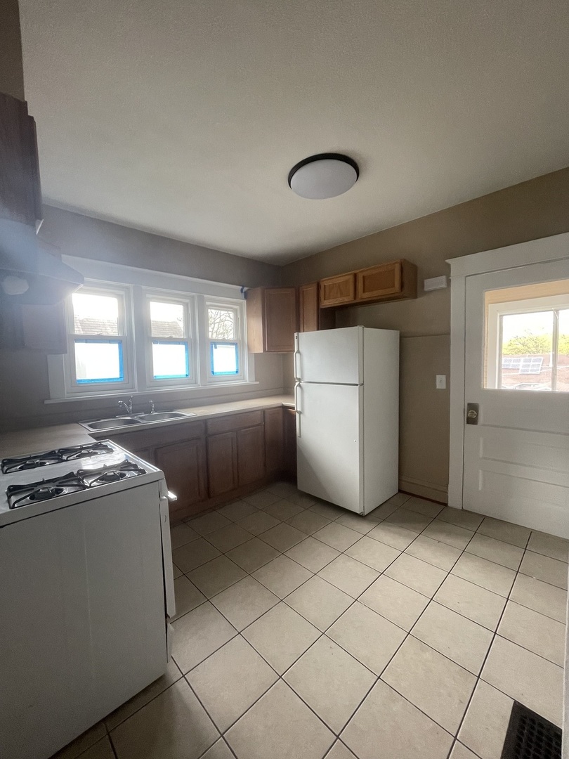 710 North Poplar Street, Unit 2 Waukegan, IL 60085 - Photo 13 of 16 a kitchen with a stove a refrigerator and white cabinets
