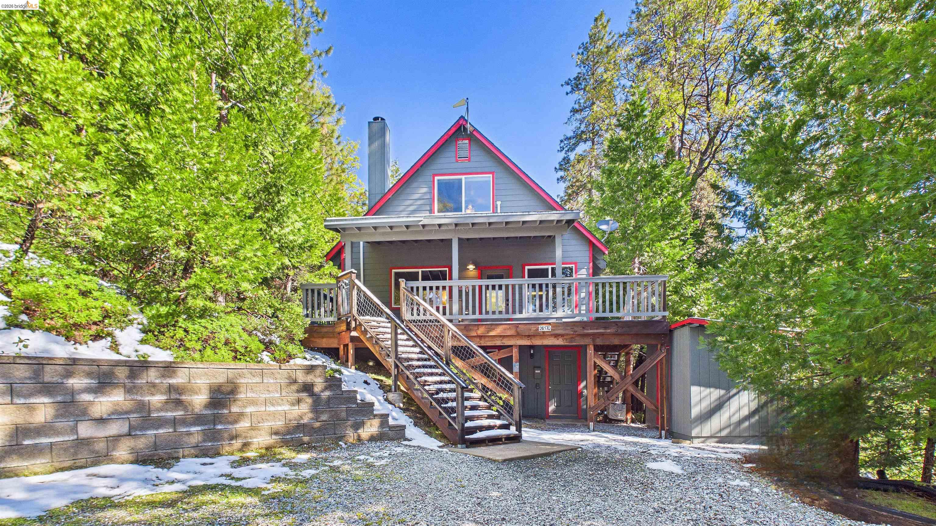 Multi-level residence featuring a gray exterior with red trim accents, a front balcony, and a prominent exterior staircase