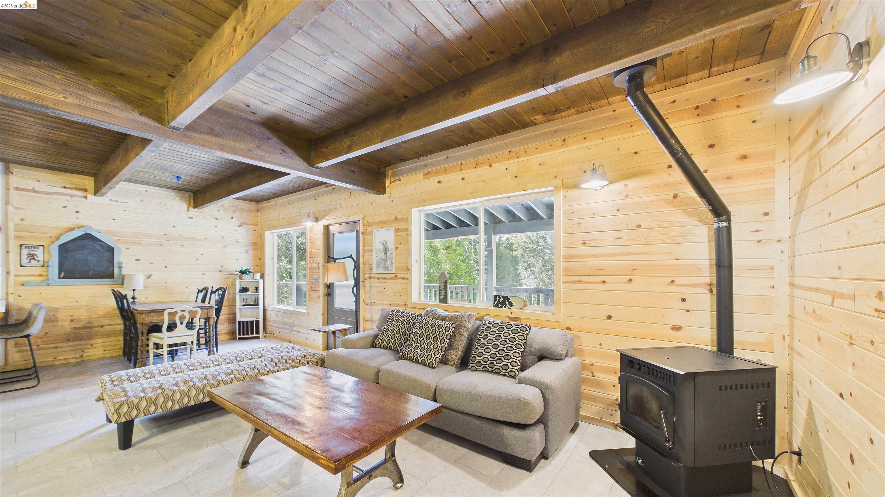 26570 Crystal Road Long Barn, CA 95335 - Photo 11 of 39 Expansive living area featuring wood-paneled walls, exposed wood ceiling beams, and light-tone flooring
