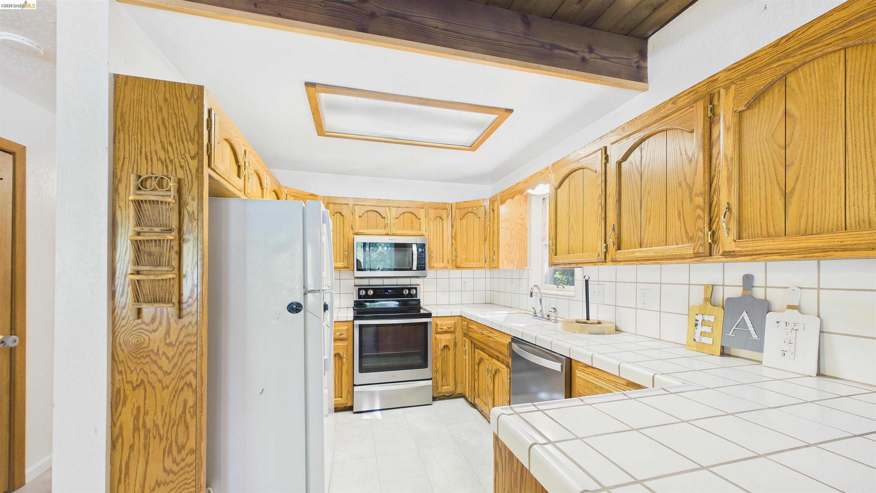 26570 Crystal Road Long Barn, CA 95335 - Photo 12 of 39 Kitchen featuring light wood cabinetry, white tiled countertops, and a white tiled backsplash