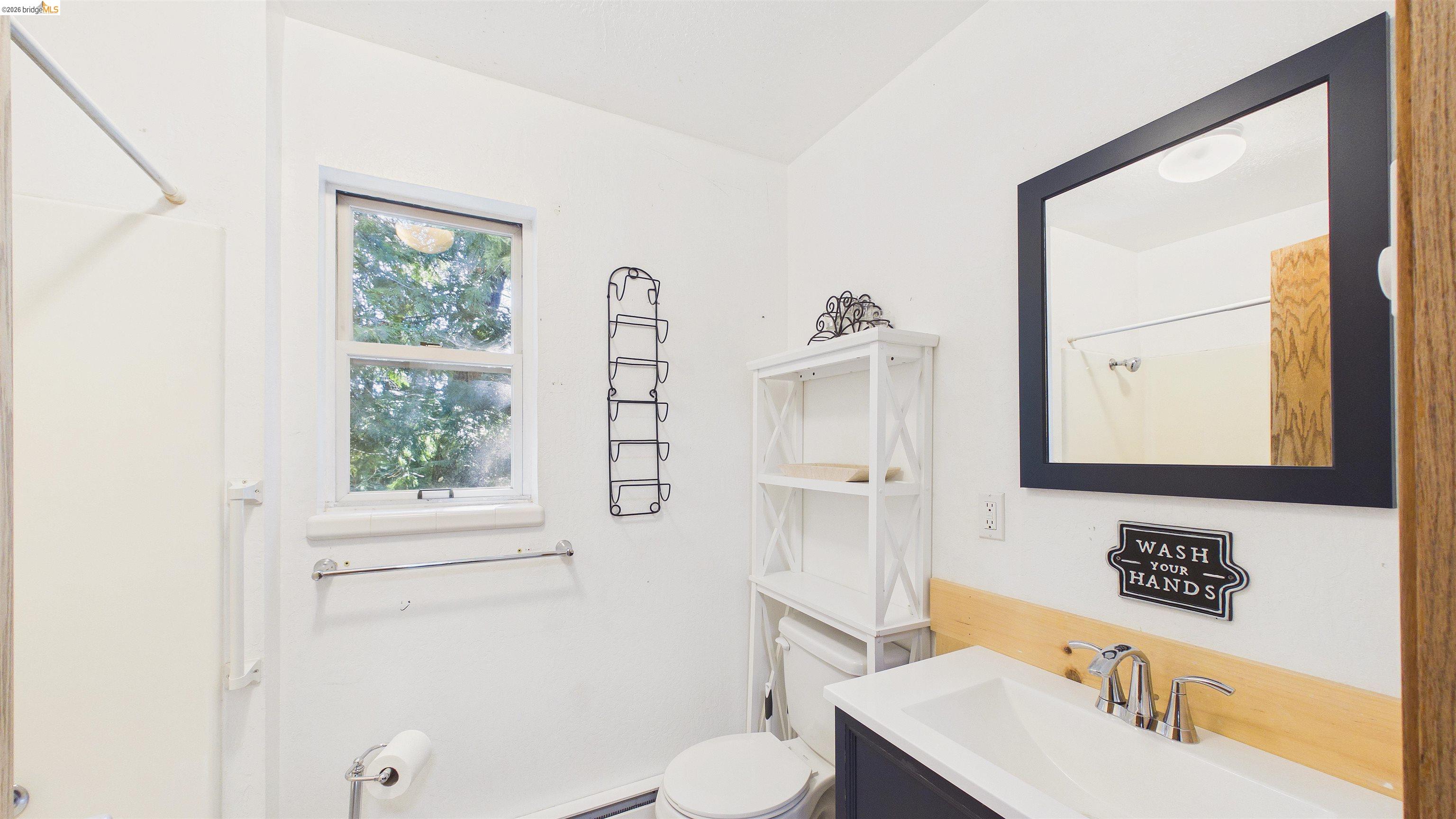 26570 Crystal Road Long Barn, CA 95335 - Photo 16 of 39 Bathroom featuring a single window, a dark-framed mirror, a vanity with an integrated sink, a chrome faucet, and a toilet
