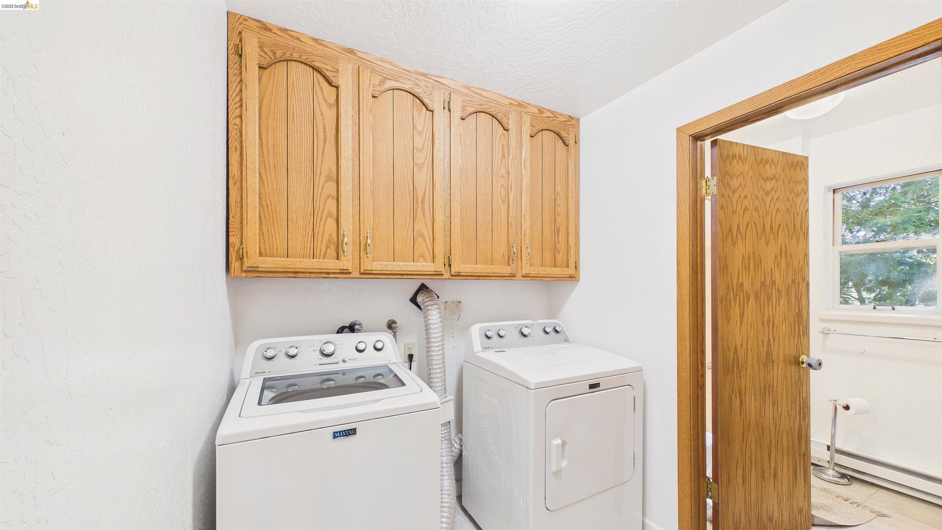 26570 Crystal Road Long Barn, CA 95335 - Photo 17 of 39 Laundry area featuring wood-finish cabinetry, white washer and dryer, and a neutral color palette