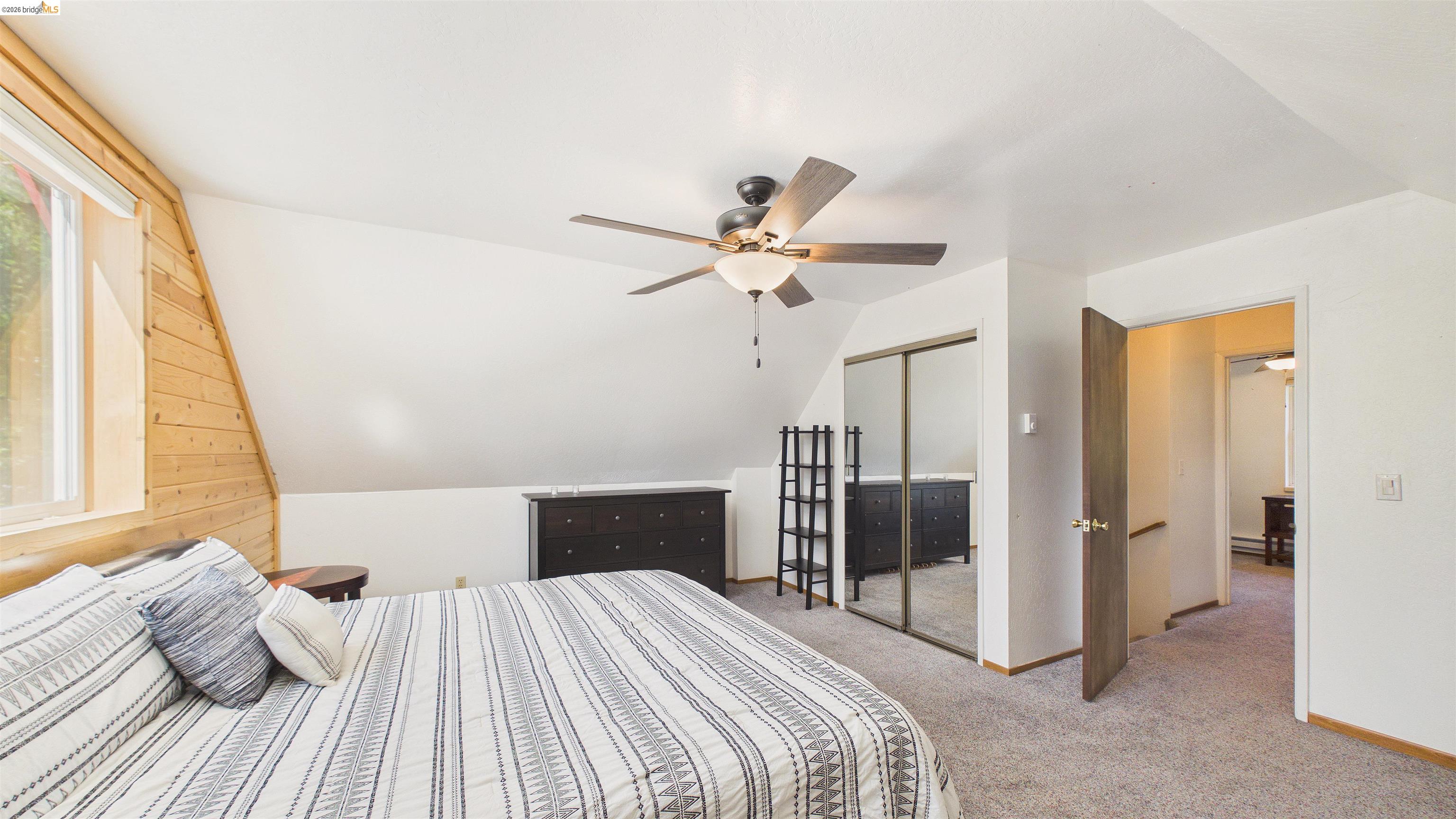 26570 Crystal Road Long Barn, CA 95335 - Photo 19 of 39 Bedroom featuring a sloped ceiling with wood paneling, a large window, neutral carpeting, a ceiling fan with integrated lighting, and mirrored closet doors