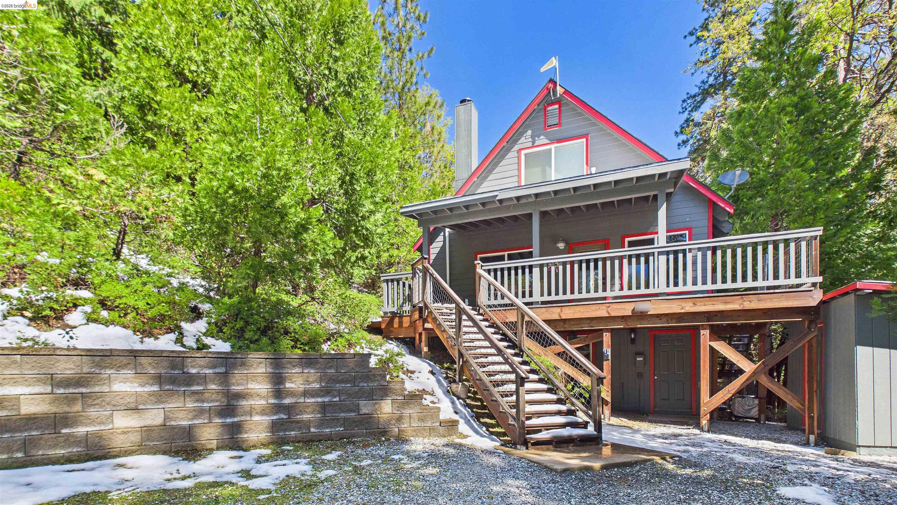 26570 Crystal Road Long Barn, CA 95335 - Photo 2 of 39 Multi-level residence featuring a gray exterior with red trim accents, a front balcony with wood railing, and an exterior staircase leading to the main entrance