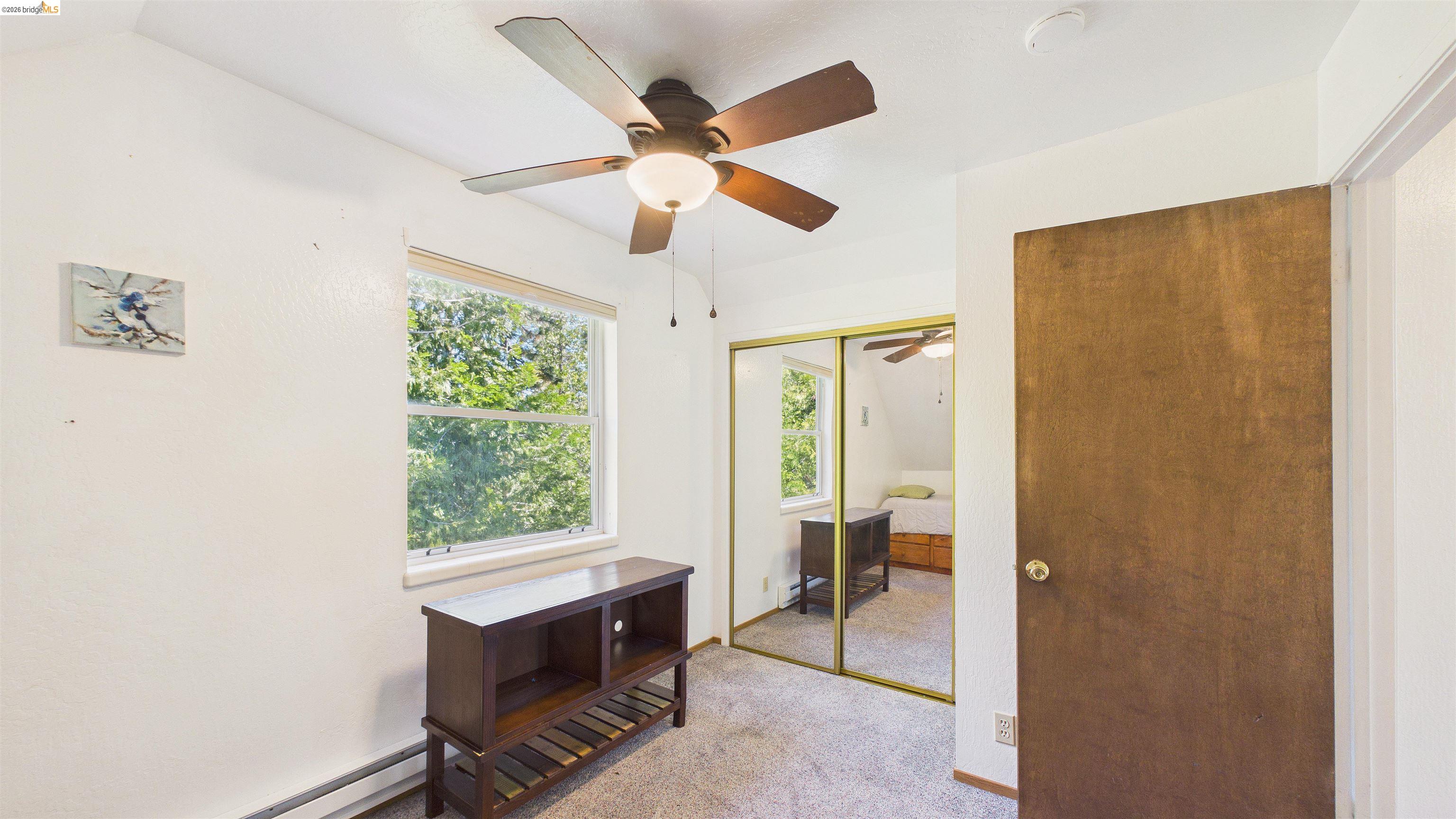 26570 Crystal Road Long Barn, CA 95335 - Photo 21 of 39 Bright room featuring a window with exterior views, a ceiling fan with integrated lighting, and mirrored closet doors