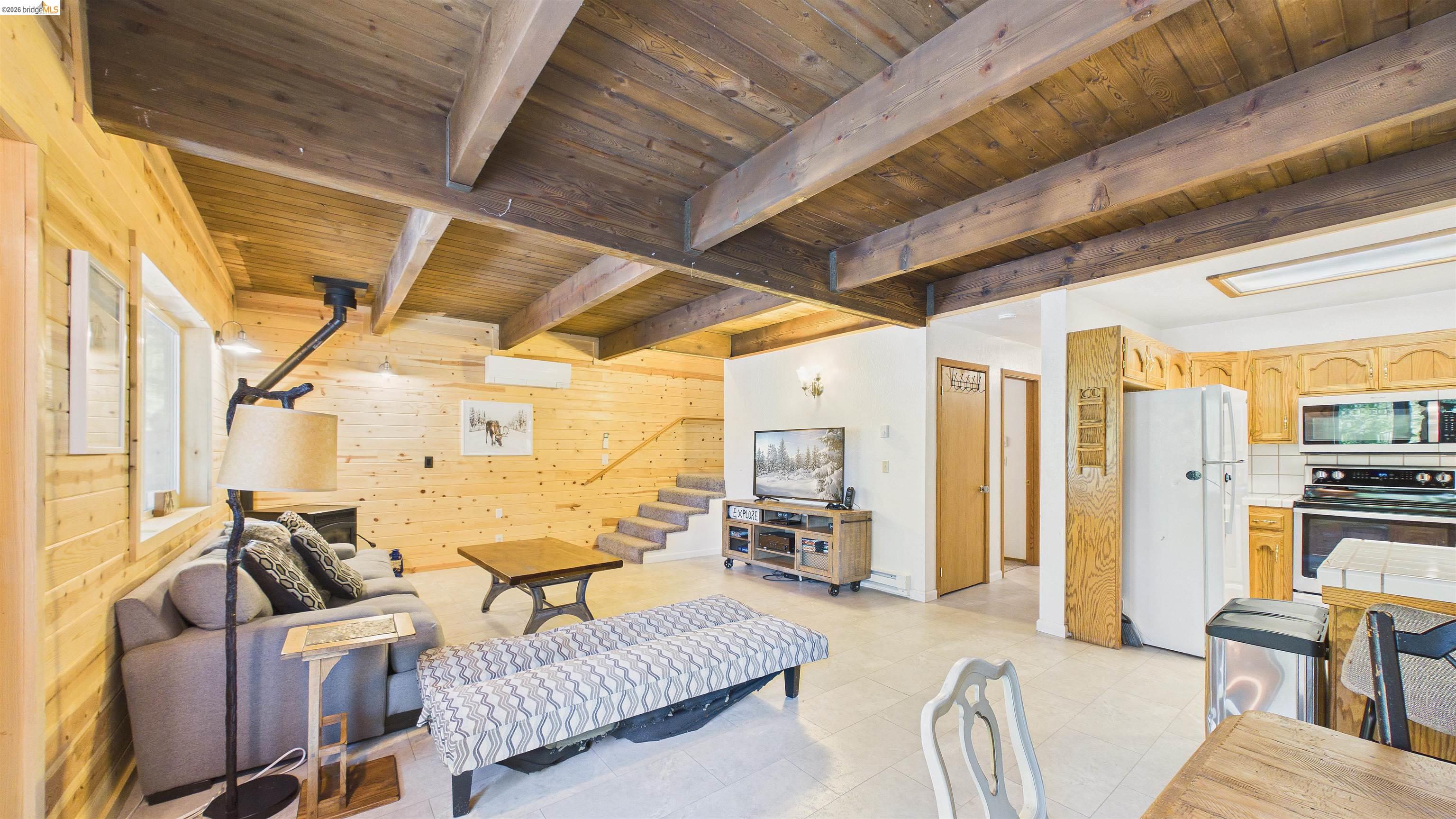 26570 Crystal Road Long Barn, CA 95335 - Photo 8 of 39 Open-concept living area featuring wood-plank walls, exposed wood beam ceiling, and ceramic tile flooring