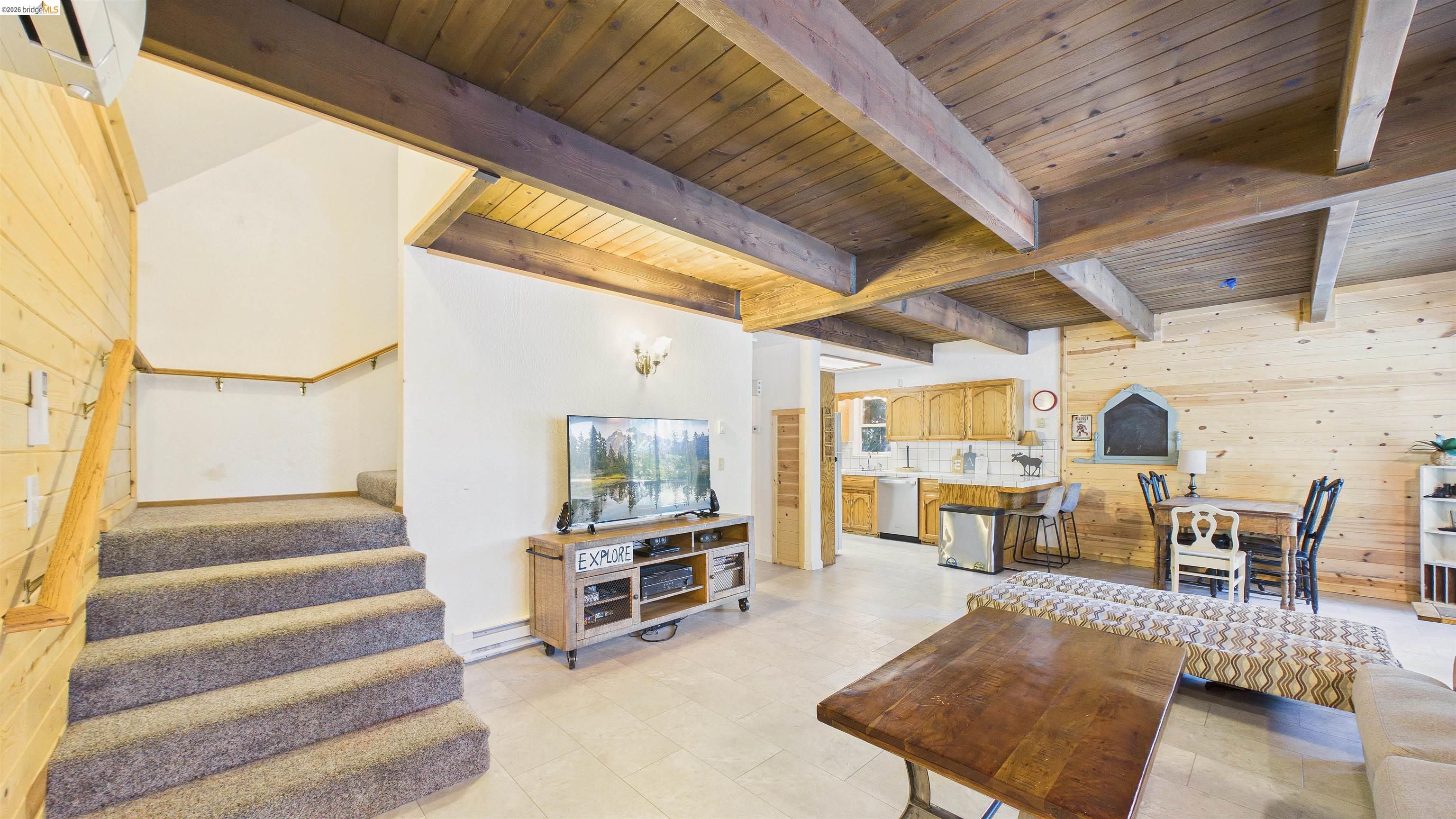 26570 Crystal Road Long Barn, CA 95335 - Photo 9 of 39 Open-concept living area featuring a wood-plank ceiling with exposed beams, wood-plank wall paneling, and light-toned flooring