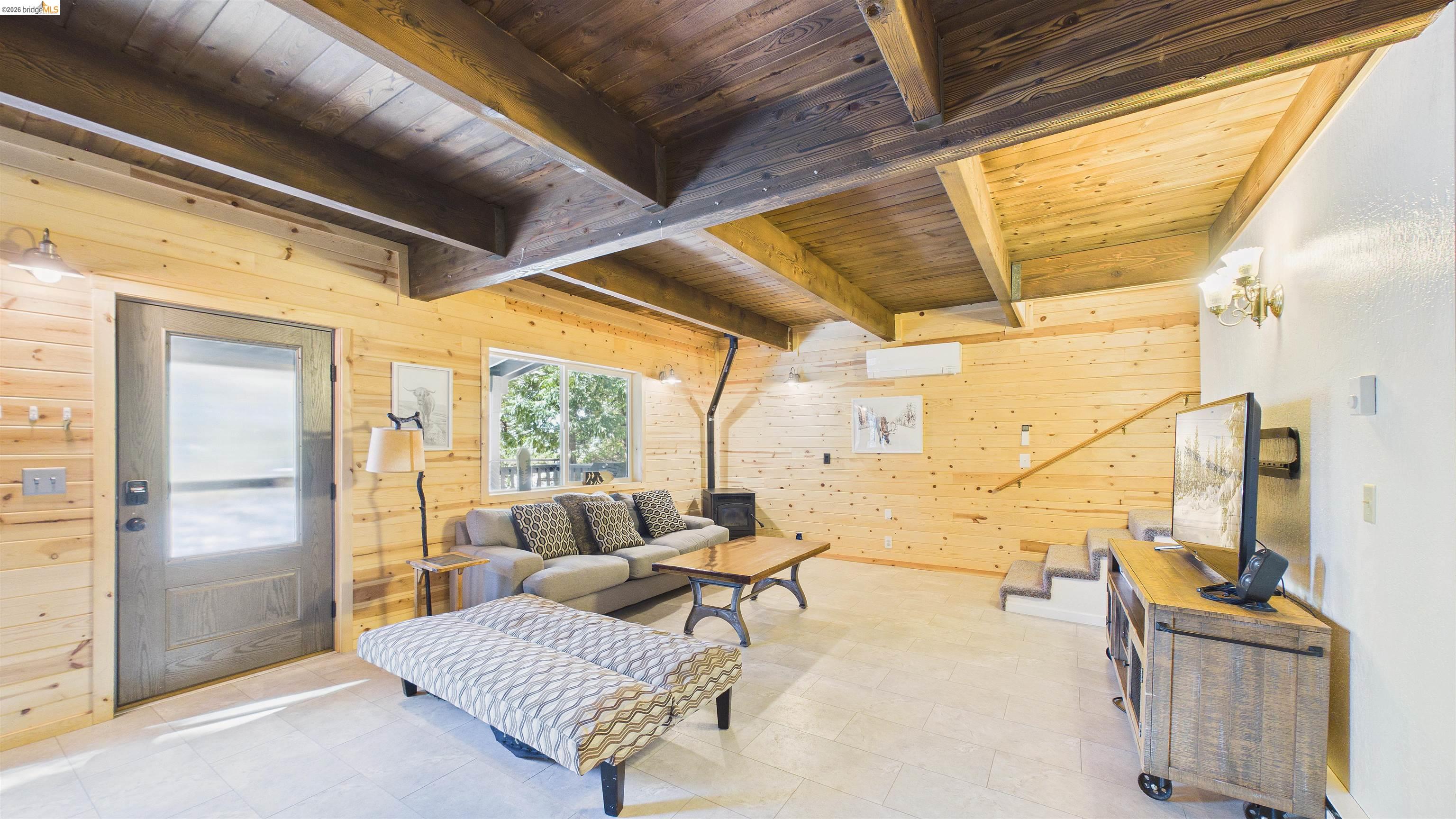 26570 Crystal Road Long Barn, CA 95335 - Photo 10 of 39 Living area featuring a prominent wood beam ceiling, light wood-paneled walls, and light-toned tile flooring