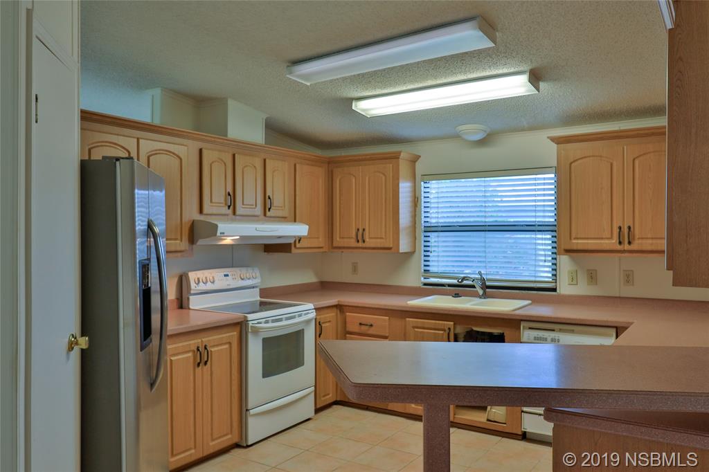 803 Navigators Way Edgewater, FL 32141 - Photo 10 of 27 a kitchen with kitchen island granite countertop a sink cabinets and stainless steel appliances