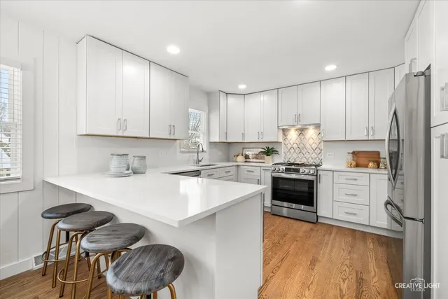 a kitchen with granite countertop a stove top oven a sink dishwasher a dining table and chairs with wooden floor