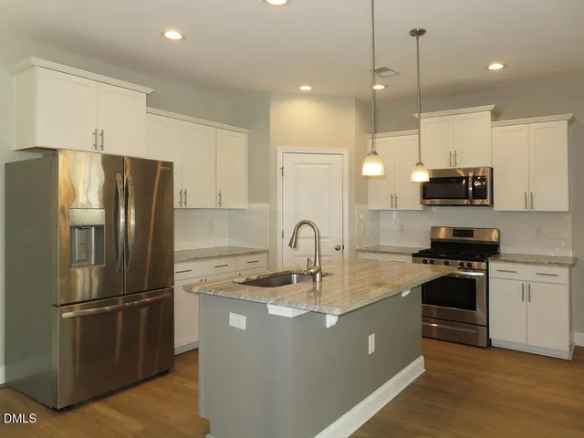 a kitchen with kitchen island a counter space a sink appliances and cabinets